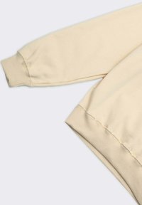 Felpa beige con una vestibilità morbida, polsini a costine e una consistenza soffice. Presenta un design semplice senza motivi o accenti.