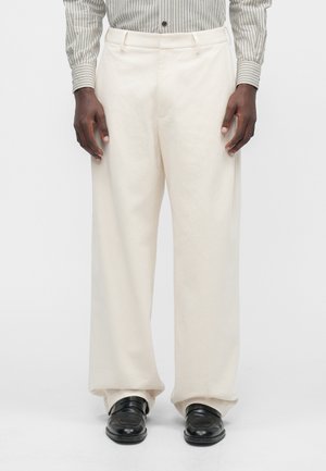 Krēmkrāsas platās bikses, izgatavotas no mīksta auduma, ar vienkāršu dizainu, gludu tekstūru un smalkiem krokām.