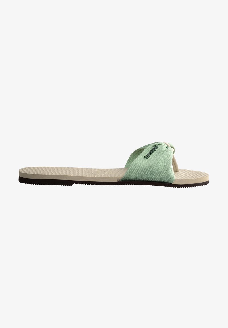 Sandale en textile vert à enfiler avec un design de bandeau noué, dessus à motifs et semelle beige texturée avec une semelle extérieure en caoutchouc foncé.