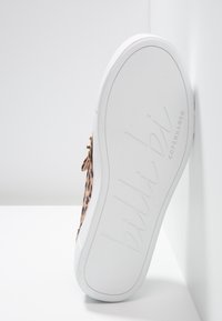 Sneaker mit weißer Sohle, einem Leopardenmuster-Obermaterial aus strukturiertem Stoff, goldenen Akzenten und geprägtem Branding auf der Sohle.