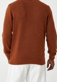 Suéter color óxido con tejido texturizado, cuello redondo y borde acanalado en el dobladillo y los puños, con un ajuste relajado.