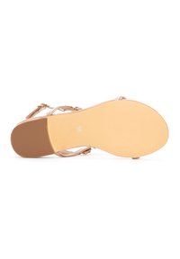 Sandalia de color oro rosa con suela plana, diseño de tiras y una pequeña hebilla. Talla 36 marcada en la parte inferior, fondo texturizado para agarre.