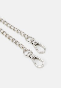 Srebrny metalowy łańcuch z dwoma karabińczykami na każdym końcu. Ogniwa mają owalny kształt i są połączone, co zapewnia trwałą i elastyczną konstrukcj�ę.