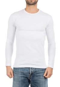 Witte longsleeve T-shirt met ronde hals, gemaakt van een gladde, rekbare stof. Draagt met blauwe denim jeans.