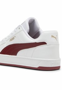 Valge nahast sneakerid, millel on kaardus marooni värvi triip, kuldne Puma logo, polsterdatud kaelus ja tekstureeritud kummist tald. Omab klassikalist madala äärega disaini.