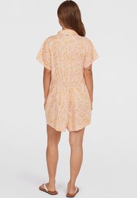 Romper à manches courtes et col, de couleur rose clair, avec un motif floral tourbillonnant, taille cintrée et short court. Tissu léger, design décontracté.