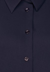 Camicia blu navy con colletto, dotata di quattro bottoni, tessuto liscio e leggero lucido. Design semplice, senza motivi.
