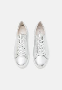 Baskets métalliques argentées avec bout arrondi, laçage à l'avant, surface en cuir lisse et semelle blanche profilée basse. Marquage subtil sur la semelle intérieure.