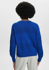 Blauer Strickpullover mit rundem Halsausschnitt, strukturierten Streifen und verlängerten Ärmeln. Der Saum ist gerippt, was dem Design Struktur verleiht.