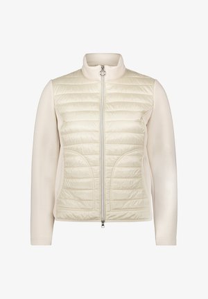 Veste légère de couleur crème avec un devant matelassé, des manches lisses, un col haut et une fermeture éclair centrale. Équipée de poches latérales et d'une silhouette ajustée.