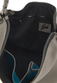 Borsa a mano in pelle grigia con chiusura a zip, presenta un interno nero e una tasca blu brillante. Include un'etichetta in pelle e cuciture visibili.