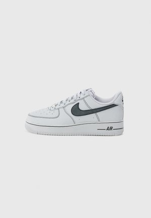 Biały sneaker Nike Air Force 1 z czarnym znakiem Swoosh, perforowanym noskiem, sznurowanym zapięciem oraz napisem "AIR" po boku podeszwy.
