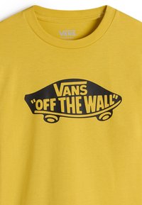 Gul bomullströja med en stor svart grafik av en skateboard som har texten "Vans" och "Off the Wall" inuti en böjd banner.