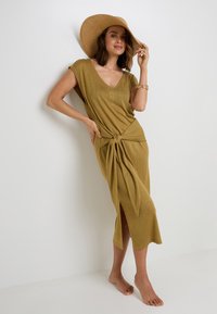 Abito maxi verde oliva con scollo a V e dettaglio annodato sul davanti, caratterizzato da una fessura laterale e maniche corte, realizzato in tessuto leggero.