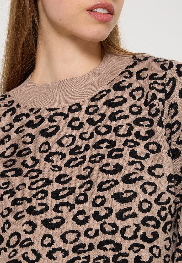 Sweter dziany w jasnym beżu z charakterystycznym czarnym wzorem w panterę; posiada prążkowany okrągły dekolt i miękką teksturę.
