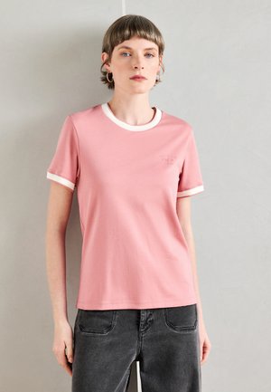 Rosa Baumwoll-T-Shirt mit einem weißen gerippten Kragen und Bündchen, versehen mit einem kleinen Logo auf der Brust, kombiniert mit dunkelgrauen Jeans.