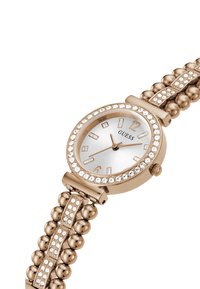 Orologio da polso Guess in oro rosa con lunetta incastonata di cristalli e bracciale a perline, quadrante bianco e lancette e indici color oro.