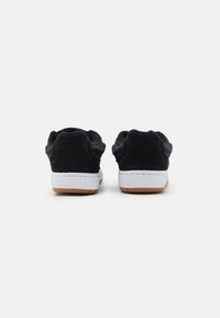 Black suede and mesh sport shoes with white midsole and textured tan rubber outsole; features rounded heel and cushioned collar.