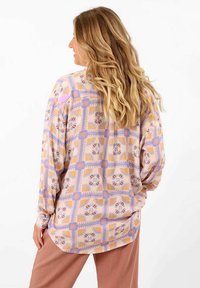 Chemise à manches longues à motifs dans des couleurs pastel avec des designs géométriques et floraux. Fabriquée en tissu doux avec une coupe décontractée et un ourlet arrondi.