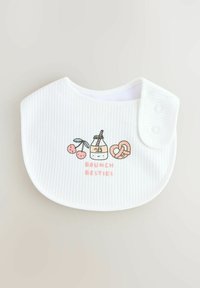 Fehér bordázott babapárna, cseresznye, tejüveg, perec és a "BRUNCH BESTIES" felirat rózsaszínben nyomtatott mintával. Kattanós záródással rendelkezik.