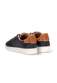Zapatillas de cuero navy con acentos de cuero marrón, forma redondeada, suela de goma blanca y cordones planos. Superficie texturizada con detalles sutiles.