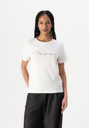 T-shirt en coton blanc avec "Champagne" écrit en texte argenté étincelant sur la poitrine. Manches courtes et col rond. Coupe ajustée.