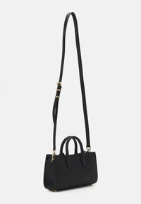 Sac à main en cuir noir avec deux poignées supérieures et une longue bandoulière réglable. Présente une forme structurée, une texture subtile et des éléments en métal doré.