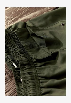 Olivgrüne Shorts aus glattem, leichtem Stoff mit elastischem Bund, verstellbarem Kordelzug und Klettverschluss-Tasche.