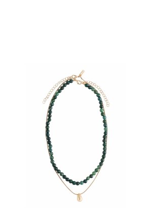 Schicht-Halskette mit dunkelgrünen runden Perlen und einer dünnen goldenen Kette, die einen kleinen unregelmäßigen goldenen Anhänger aufweist, beide mit goldenen Karabinerverschlüssen und Verlängerungsketten.