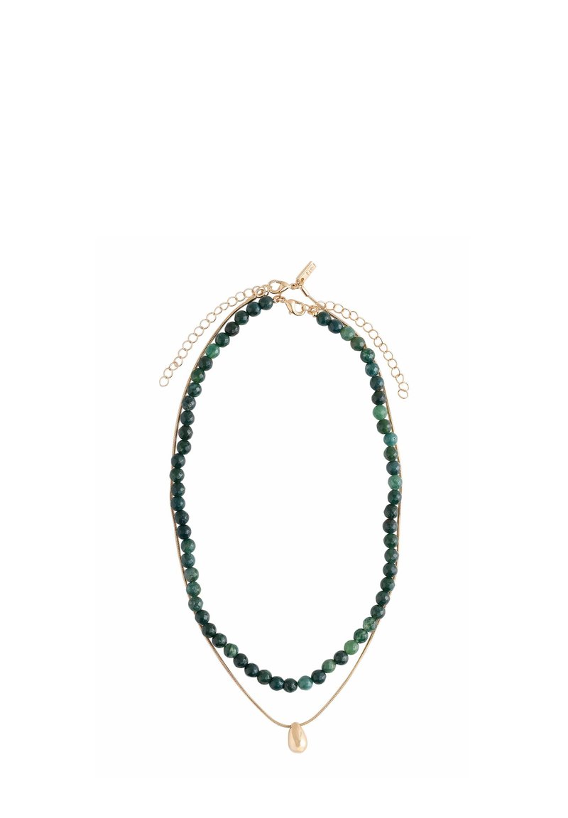 Schicht-Halskette mit dunkelgrünen runden Perlen und einer dünnen goldenen Kette, die einen kleinen unregelmäßigen goldenen Anhänger aufweist, beide mit goldenen Karabinerverschlüssen und Verlängerungsketten.