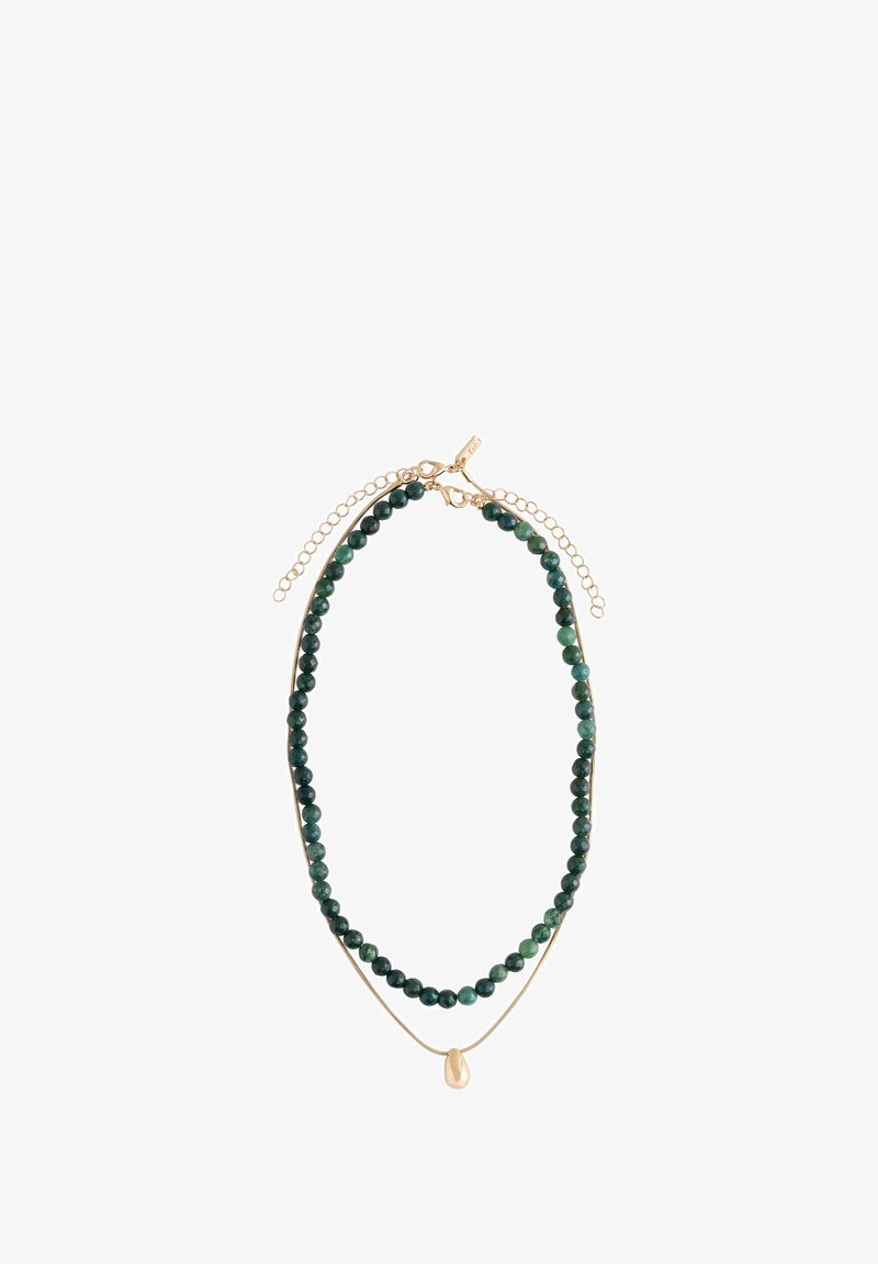 Collier en couches avec des perles rondes vert foncé et une fine chaîne en or, ornée d'un petit pendentif en or irrégulier, le tout avec des fermoirs en or et des chaînes d'extension.