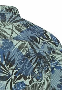 Blue and black tropical leaf pattern on light blue fabric, focusing on upper back and collar area of a shirt.