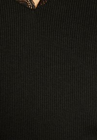 Top nero a coste con scollatura in pizzo scallop. Il tessuto ha una consistenza morbida e un design aderente, che enfatizza il motivo a coste verticali.