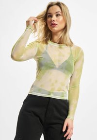 Priehľadná blúzka s dlhými rukávmi, ktorá sa vyznačuje svetlozeleným a žltým tie-dye vzorom, okrúhlym výstrihom a priliehavým strihom.
