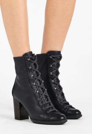 Bottines noires en cuir texturé, avec un laçage à l'avant et des œillets en métal, une pointe arrondie et un talon épais.
