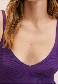 Débardeur violet côtelé avec un col en V profond et une silhouette ajustée, mettant en valeur une texture fine et des détails subtils de coutures.