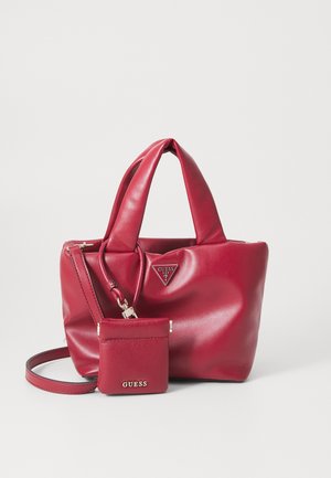 Rød Guess håndtaske med polstrede håndtag, aftagelig crossbody-rem og matchende lille pung ved fronten.