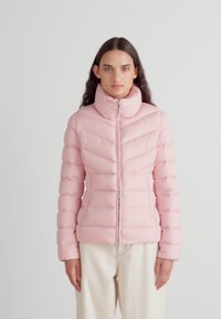 Ροζ μπουφάν με ψηλό γιακά, κλείσιμο με φερμουάρ και μοτίβο κεντητής ζιγκ-ζαγκ. Λείο ύφασμα με ελαφρώς γυαλιστερή υφή.