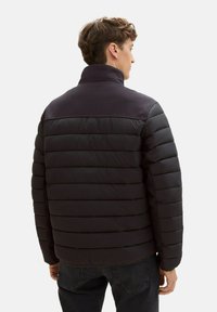 Czarna kurtka puchowa z poziomym pikowaniem, wysokim kołnierzem i trwałym materiałem. Posiada gładką fakturę i prosty krój.