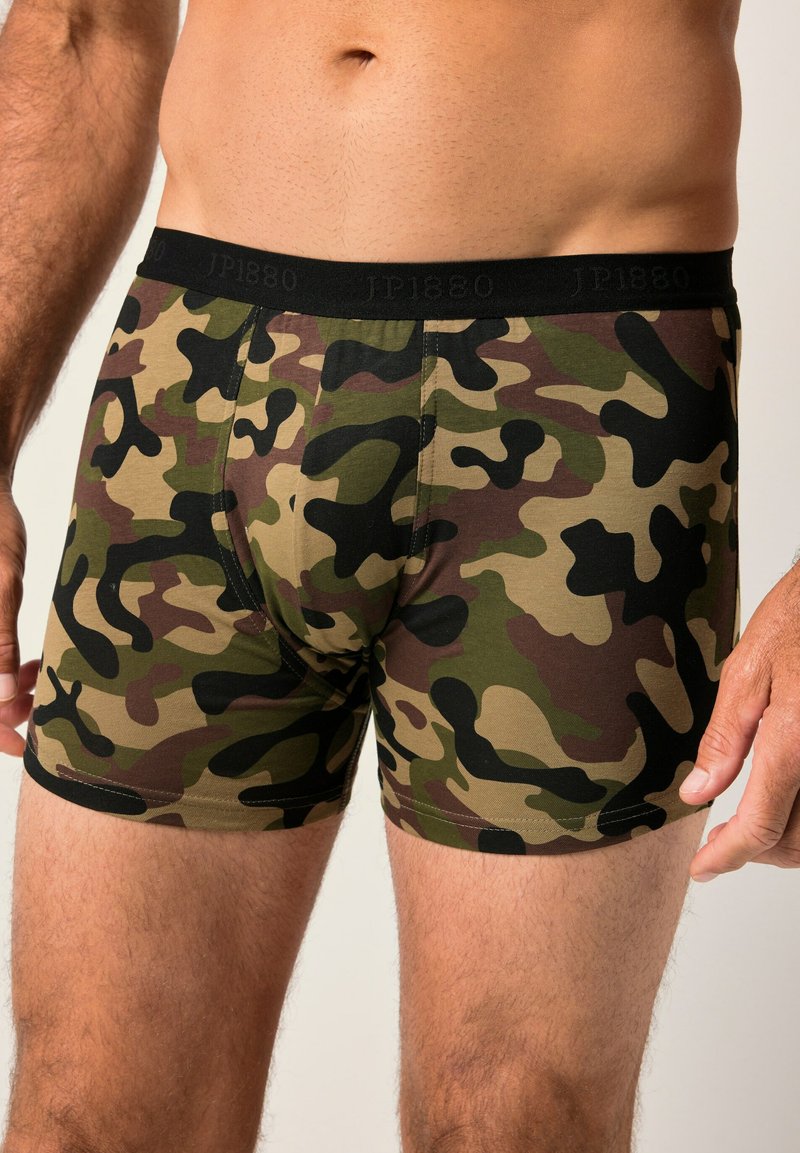 Boxer in stampa mimetica verde, marrone e nera, realizzati in morbido tessuto con una vita nera e logo. Taglio aderente con cuciture visibili.