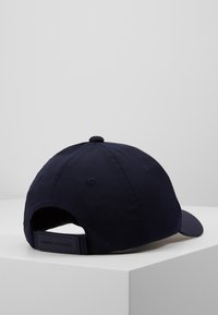 Cappello da baseball navy con visiera curva, realizzato in tessuto liscio, dotato di un bottone sulla corona e di un cinturino regolabile sul retro.