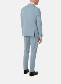 Vaaleansininen puku, jossa on teksturoitu kangas, yksi takahalkio ja mustat kengät. Malliin kuuluu kapealahkeiset housut ja räätälöity takki.