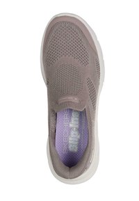 Zapato sin cordones en tejido de punto color taupe claro con perforaciones circulares. Presenta una suela de goma blanca y una plantilla texturizada con acentos morados.