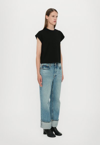 Black cropped t-shirt with capped sleeves, paired with light blue relaxed-fit jeans featuring cuffed hems and black ankle boots.