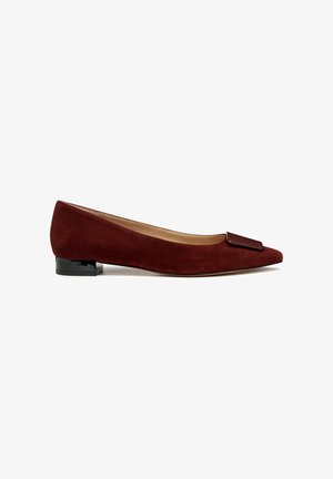 Chaussure plate en daim bordeaux avec un nez pointu et un accent rectangulaire noir sur l'empeigne. Talon bas et transparent noir. Texture lisse.