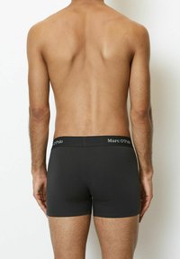 Schwarze Boxershorts mit passgenauem Schnitt und elastischem Bund, der das Logo "Marc O'Polo" trägt. Glatte Textur, minimalistische Details.