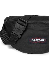 Sorte stof taljebælte med en rund form, der har en lynlåslukning, justerbar rem og et fremtrædende Eastpak-logo patch.