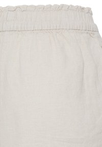Ceinture élastique avec tissu en lin beige froncé, montrant les détails de texture et de couture sur un vêtement.