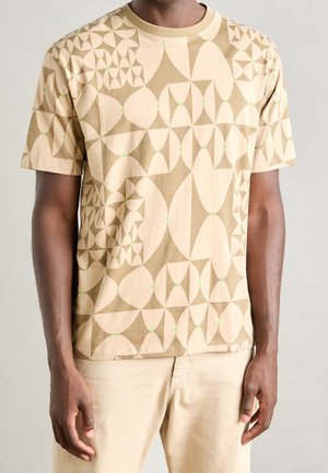 Beige Baumwoll-T-Shirt mit geometrischen Mustern in helleren Farbtönen und grünen Punkten, Rundhalsausschnitt und kurzen Ärmeln.