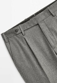 Pantalon en laine grise avec une finition texturée, doté d'une fermeture à boutons et de plis à l'avant. La taille est structurée et soigneusement ajustée.
